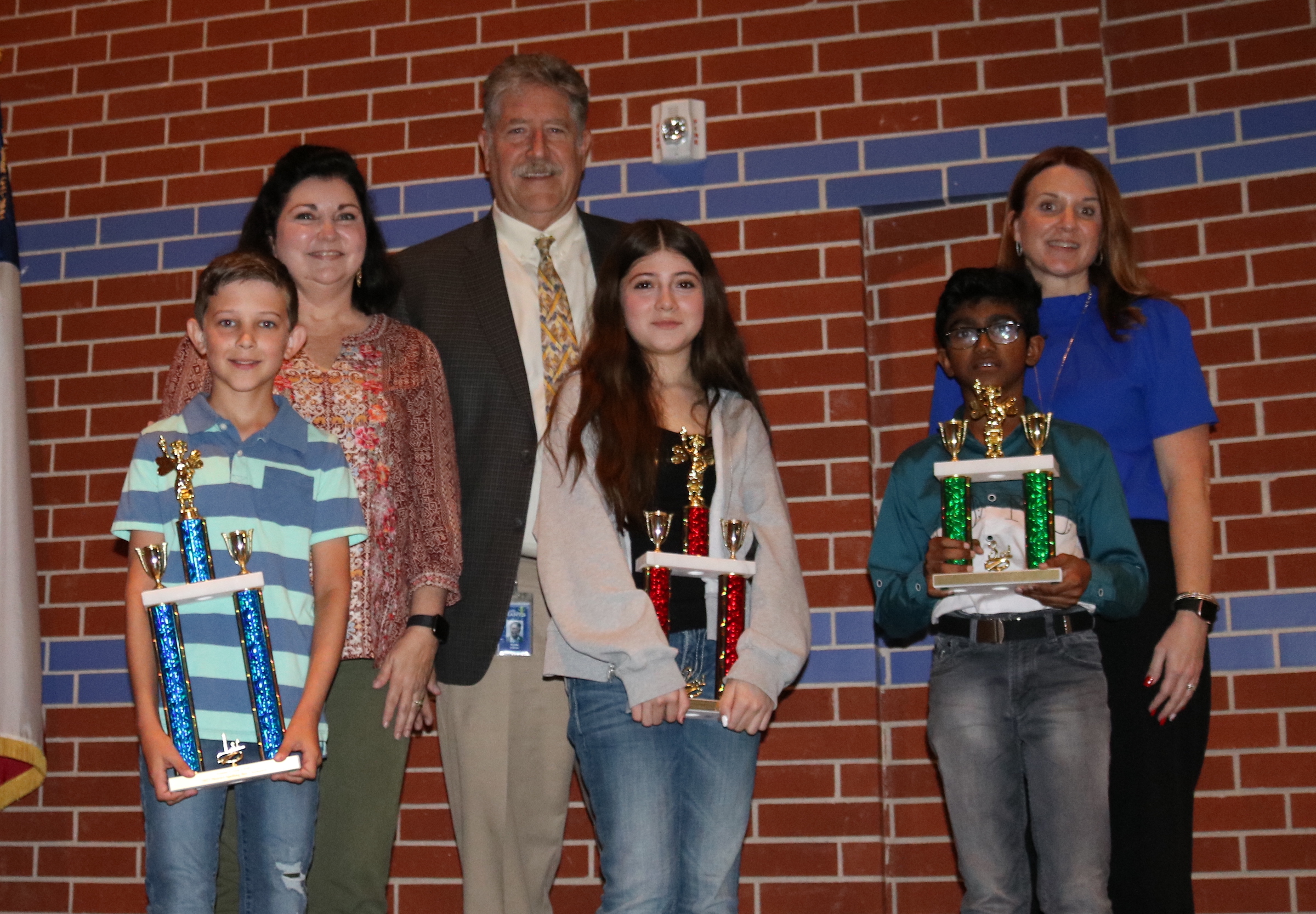 GCCISD Spelling Bee qualifiers pose with trophies, superintendent, and school principals