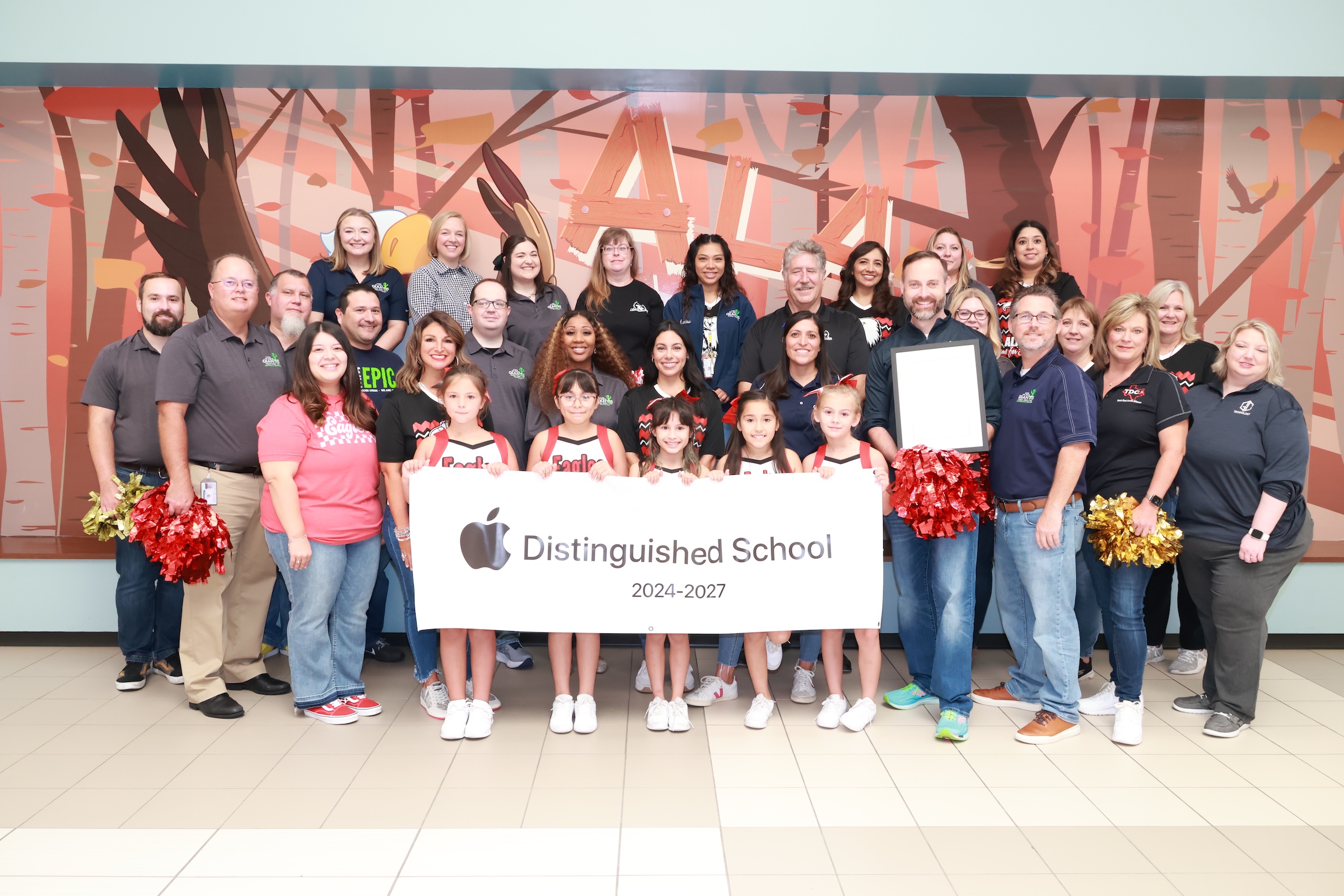 alamo elementary staff and district administration pose with alamo apple banner