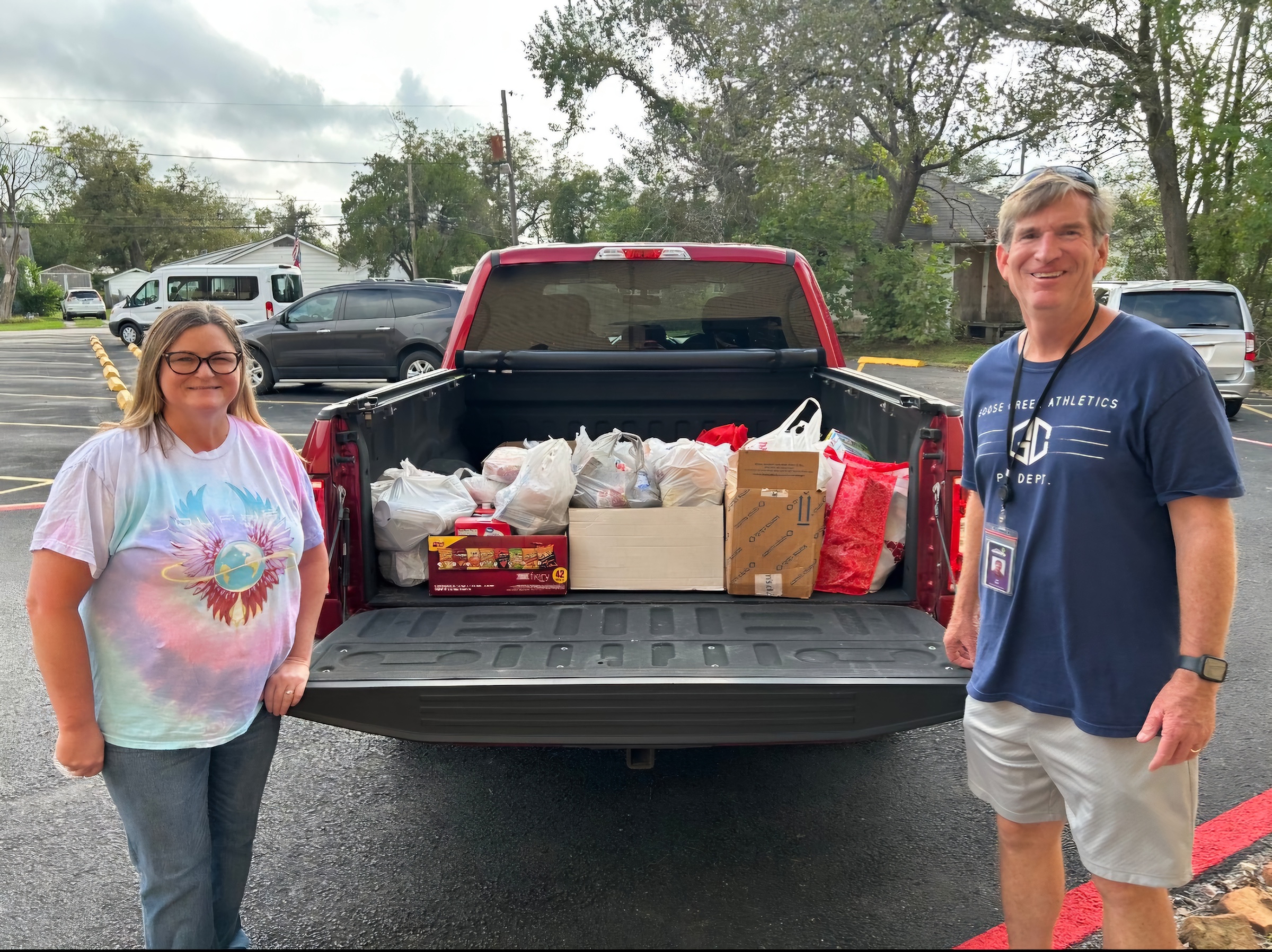 truck bed full of donated food with pe teacher and other staff member standing next to it