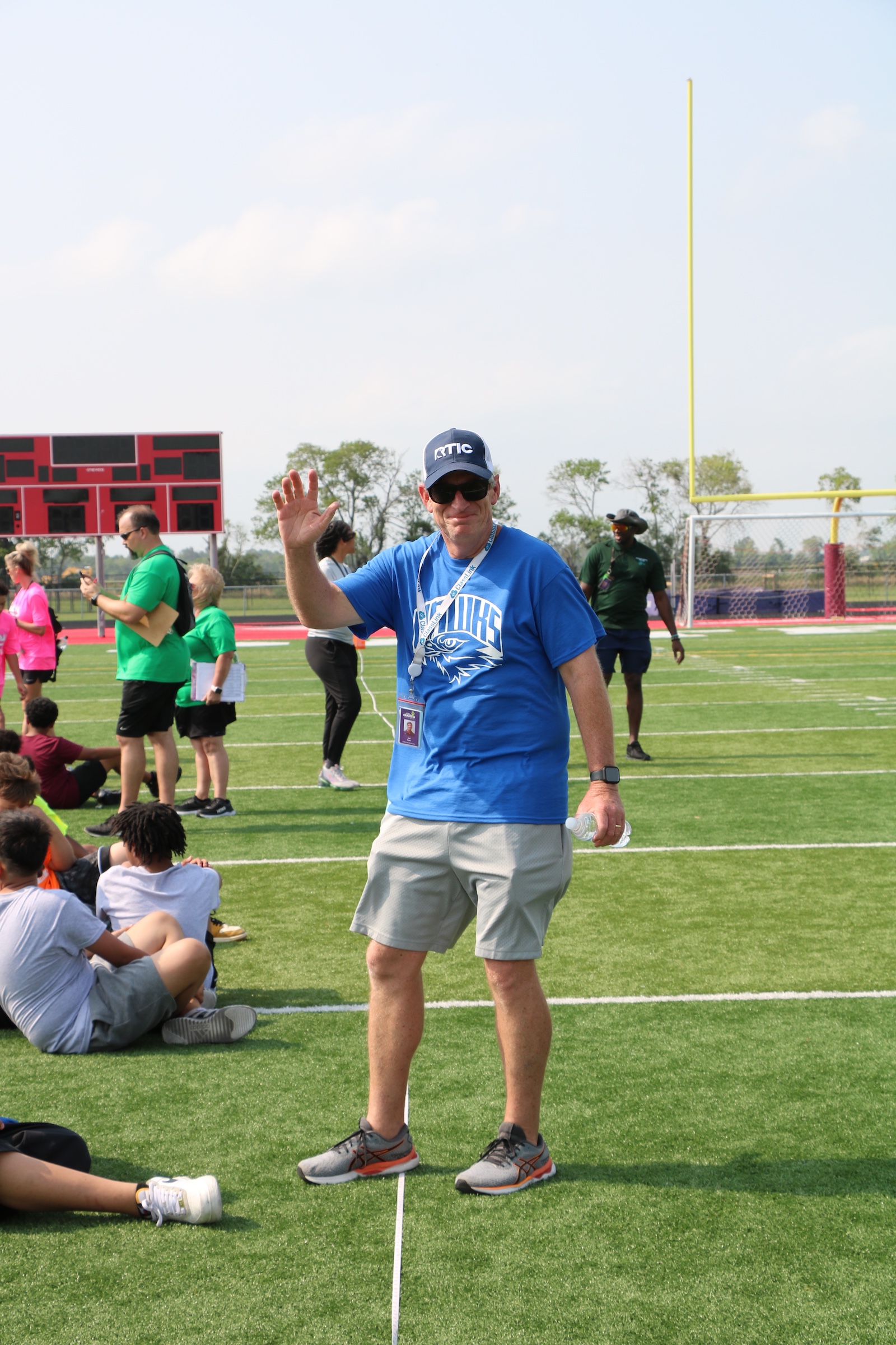 coach standing on outdoor sports field waving to camera