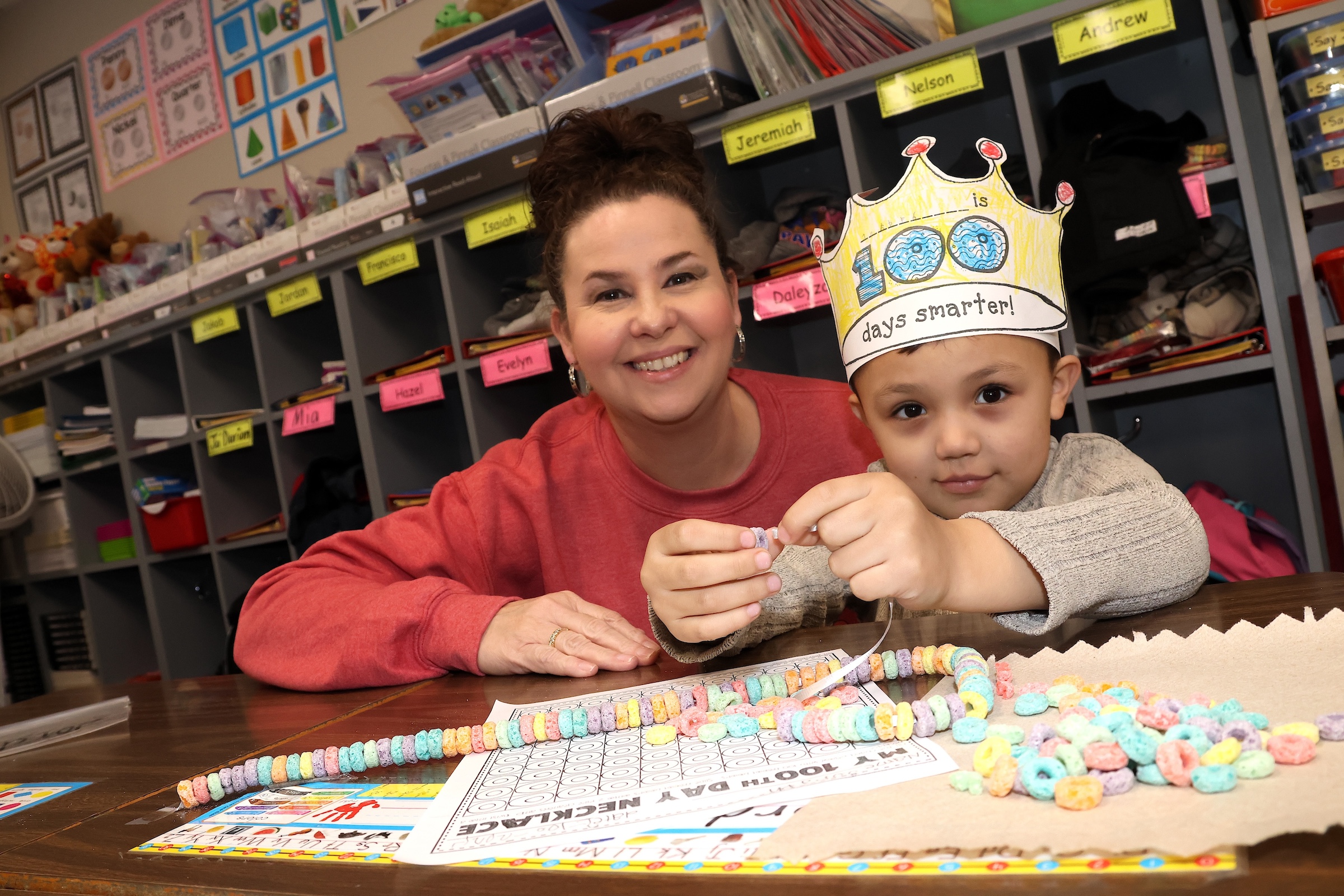 Kindergartner working on a cereal string as he counts to 100 while his teacher