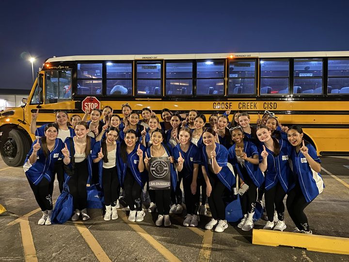 Stars pose with award in front of school bus