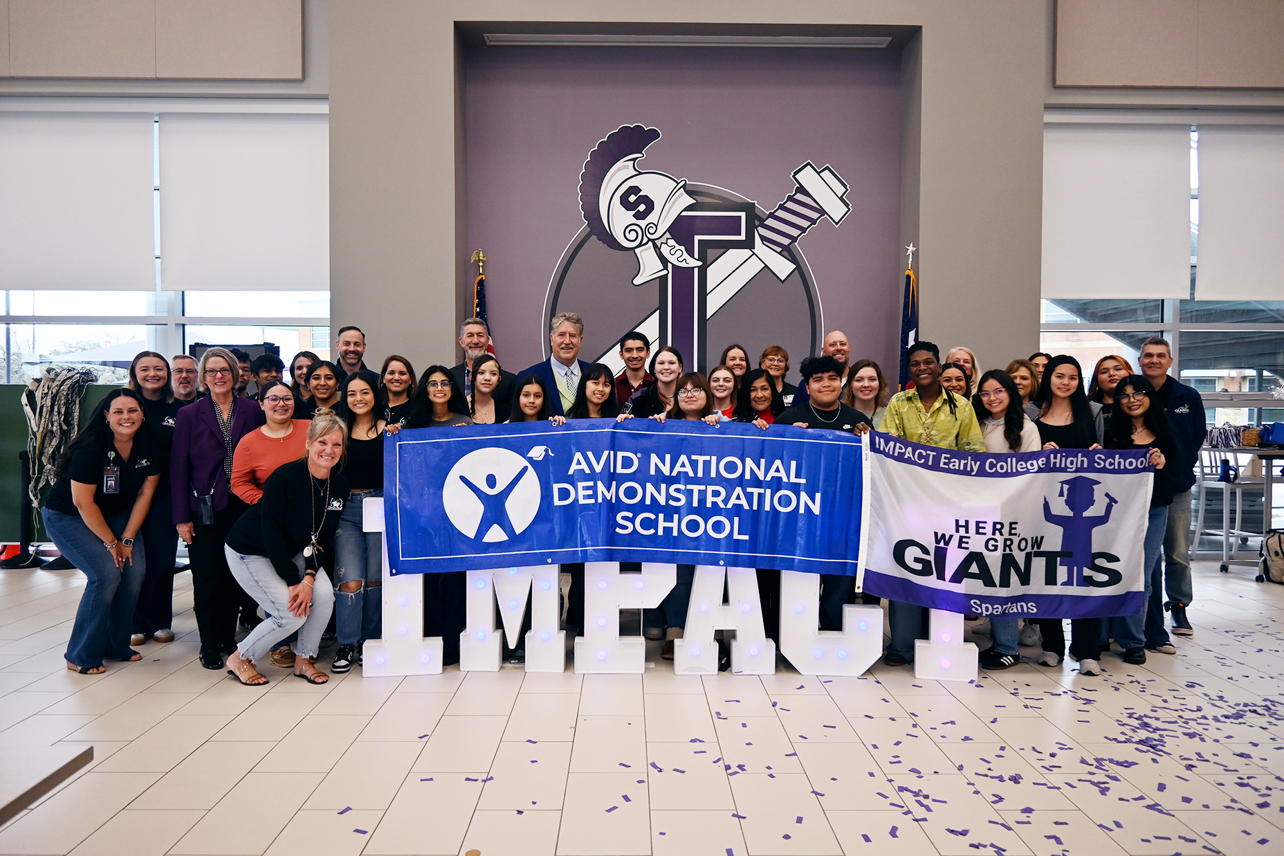 impact staff and students along with district leaders pose with AVID banner