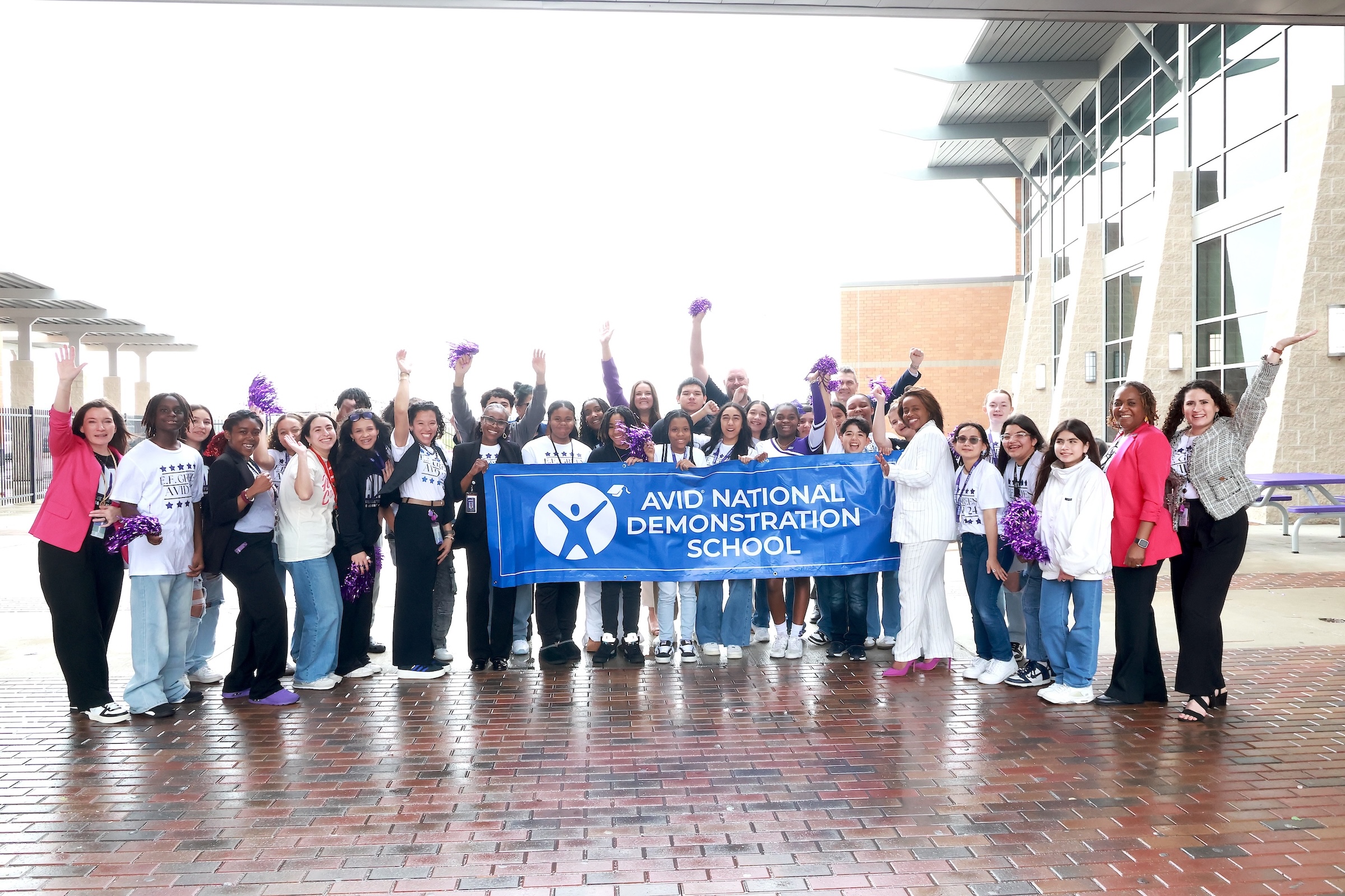 AVID representatives and students pose with demo school banner.