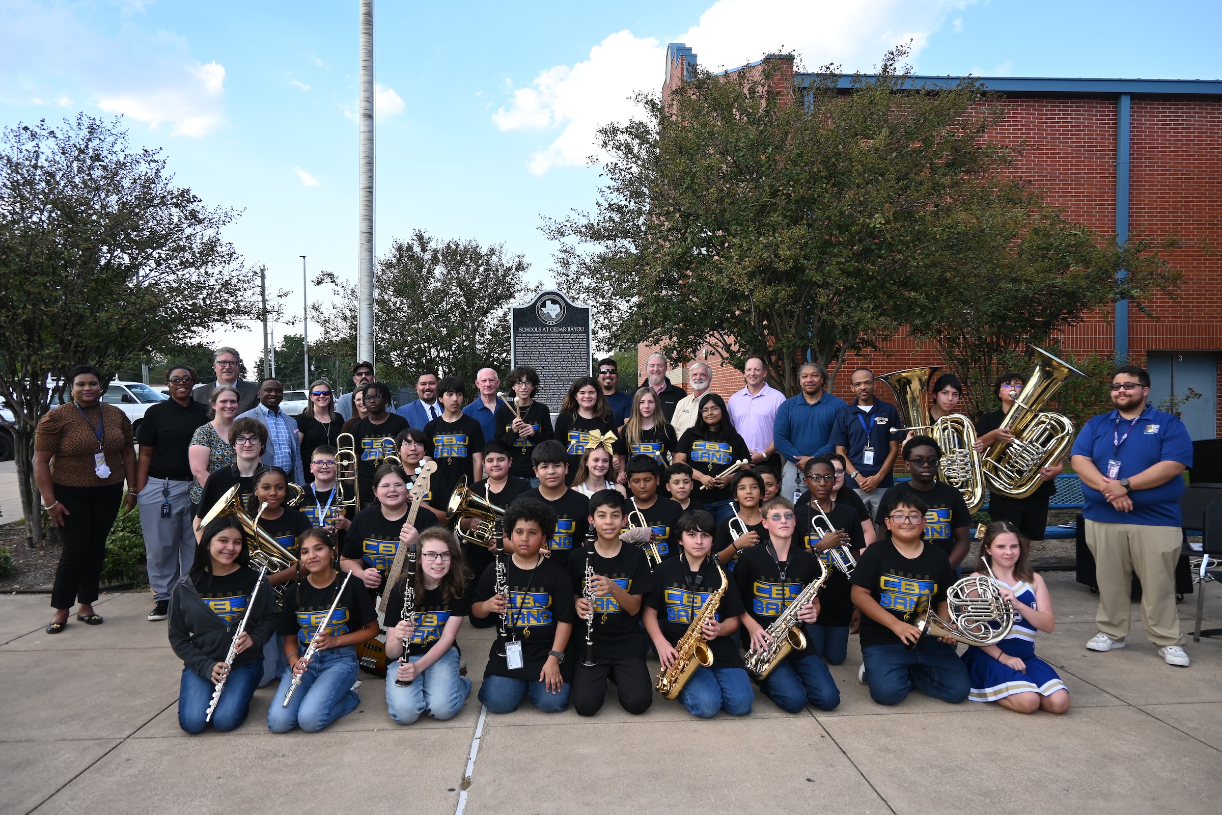 cedar bayou cheer and band students pose with plaque and campus and district leaders