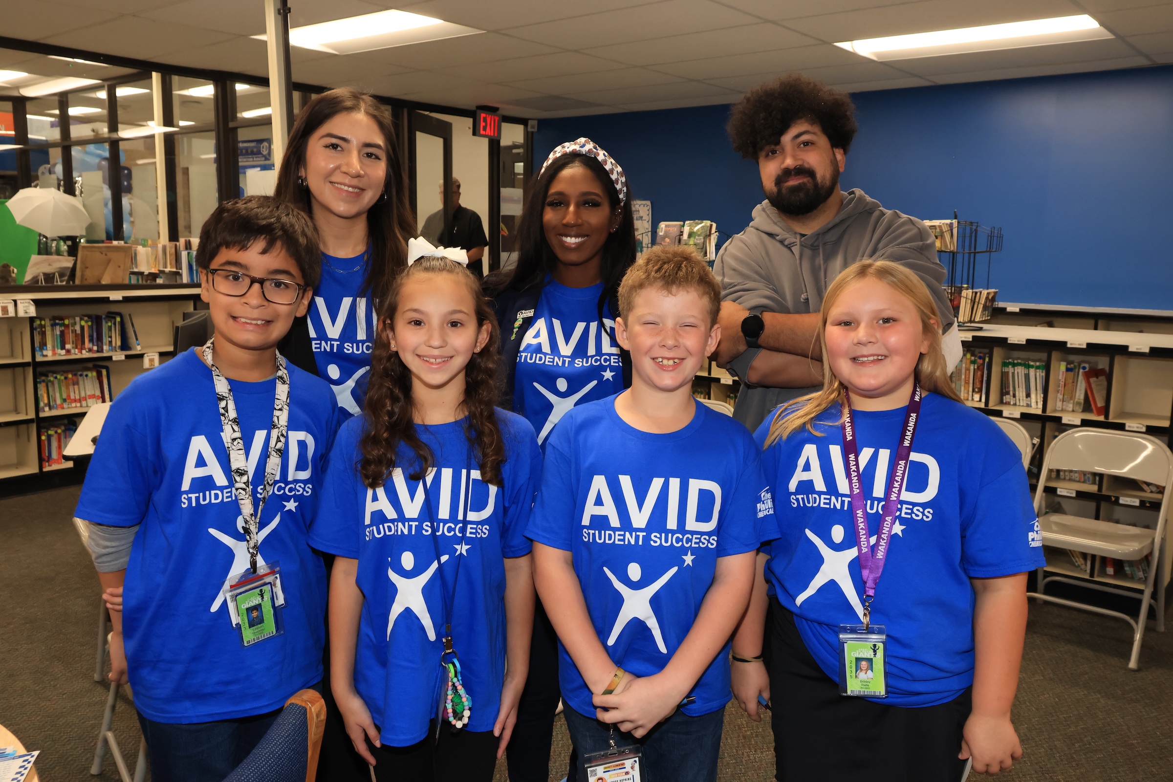 campus admin and student ambassadors pose in the library in their avid shirts