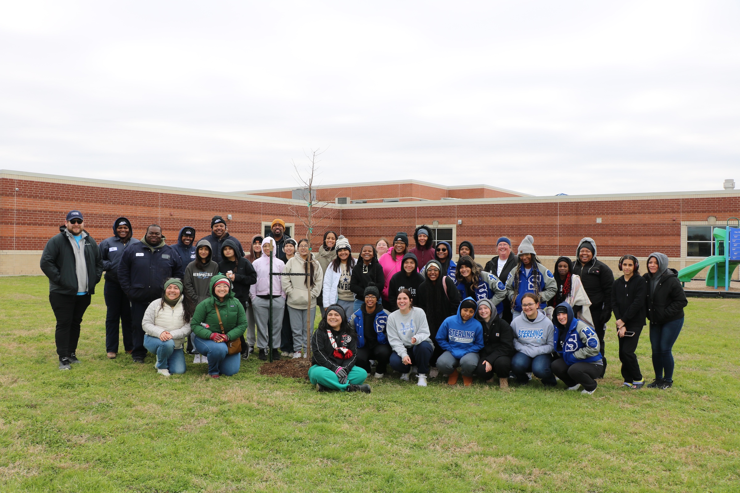 volunteers pose with tree planted outside of banuelos