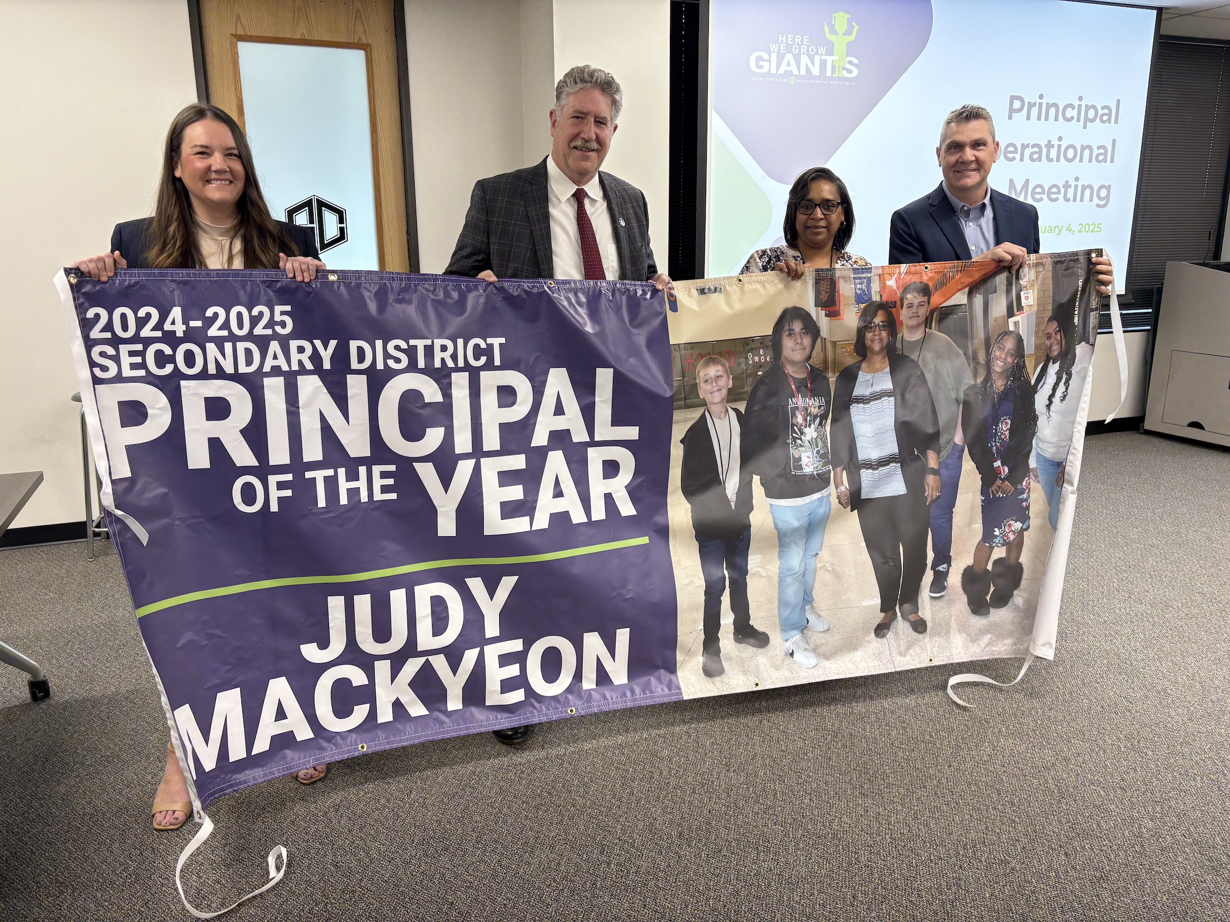 district leaders pose with mackyeon and banner announcing her as principal of the year