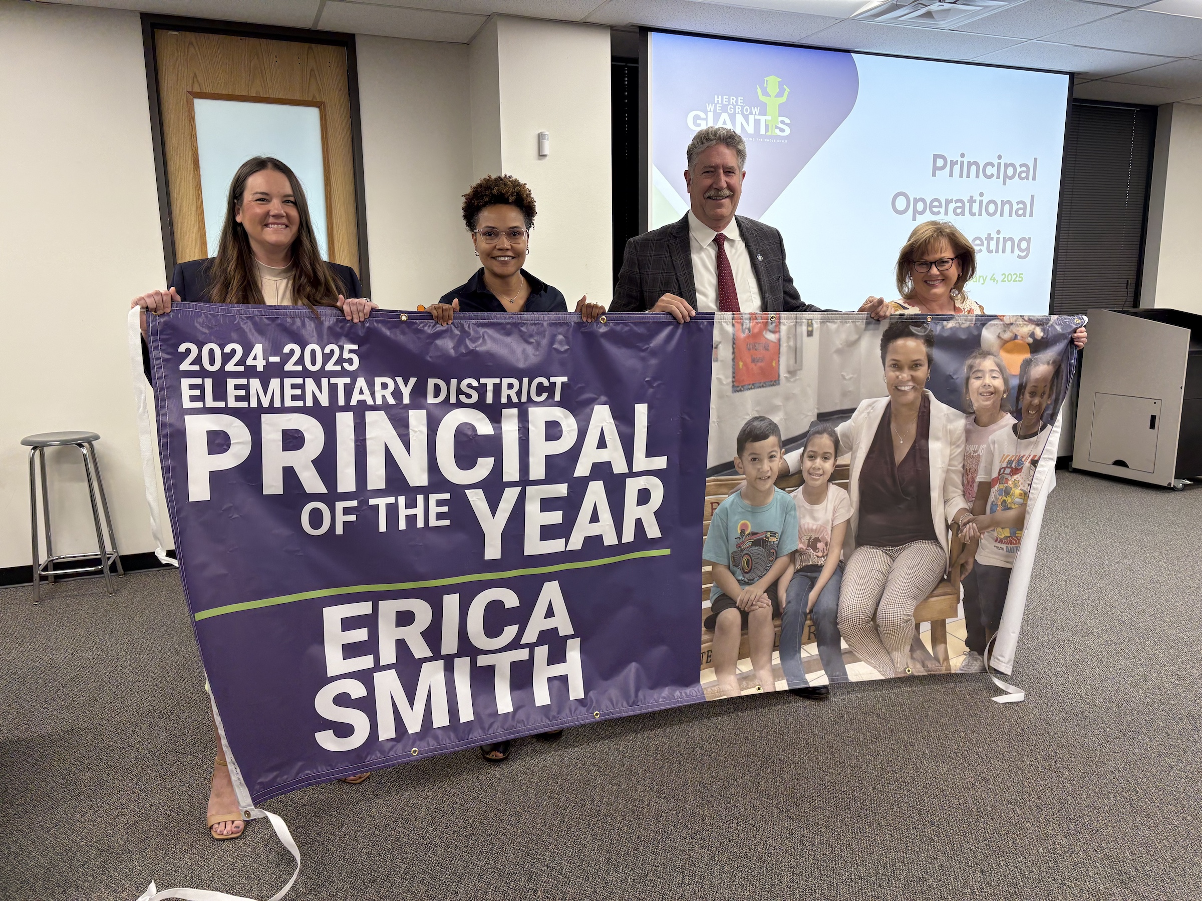 district leaders pose with erica smith and banner announcing her as principal of the year
