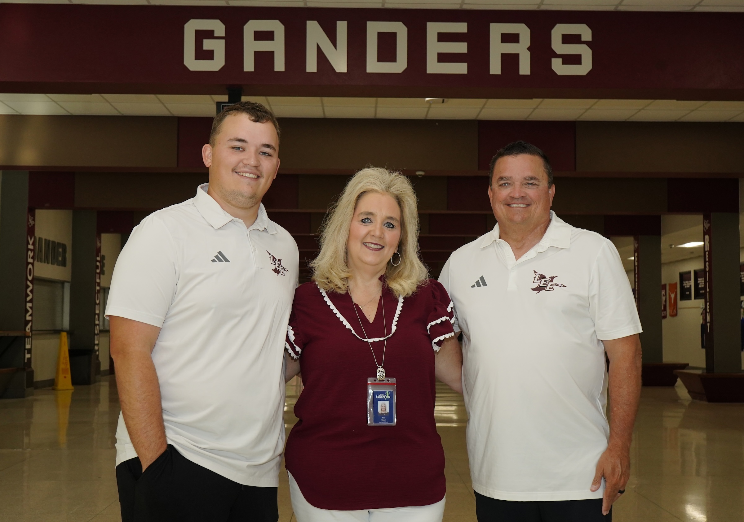 Landon, Kim, and Quinn Wood standing in the lee commons smiling wearing maroon and white