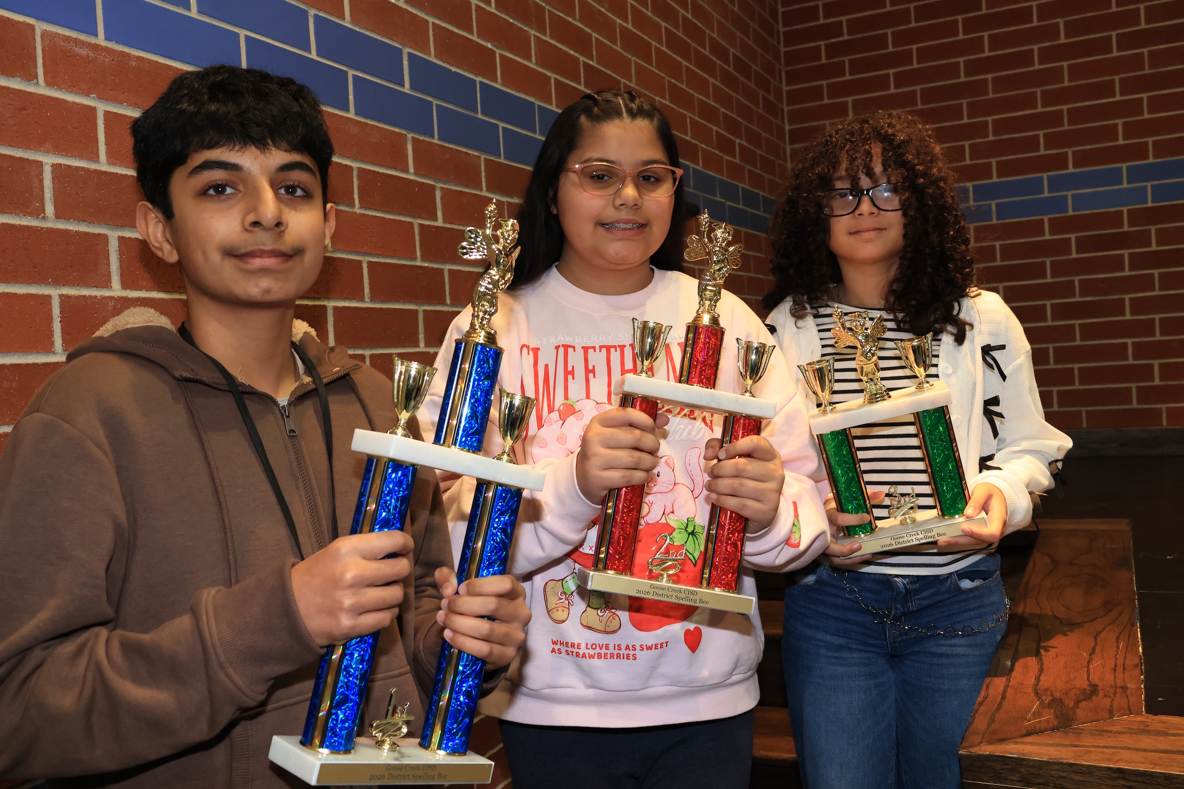 district spelling bee winners pose with their trophies