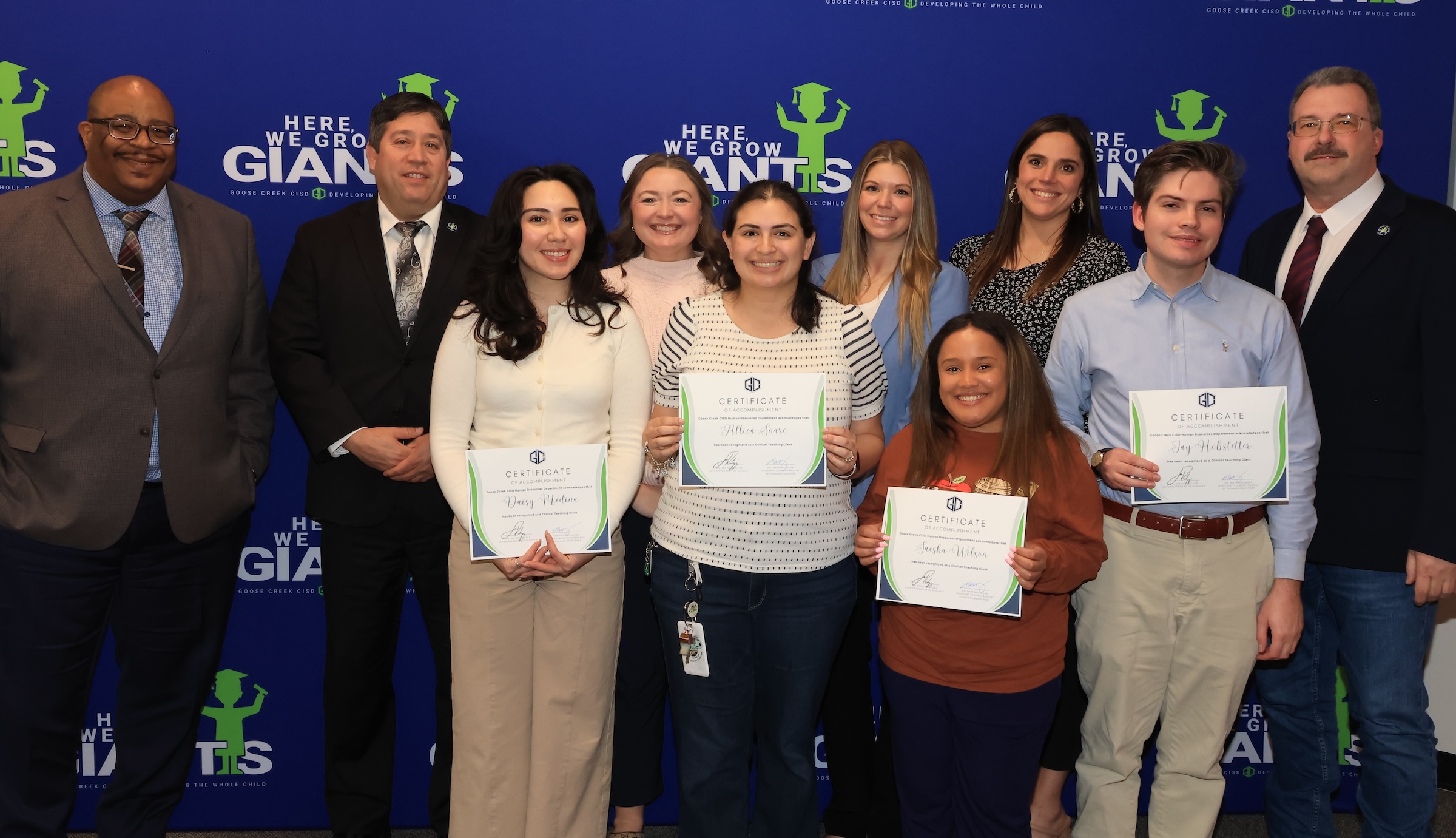 grow your own program graduates pose with certificates, district administrators, and board members