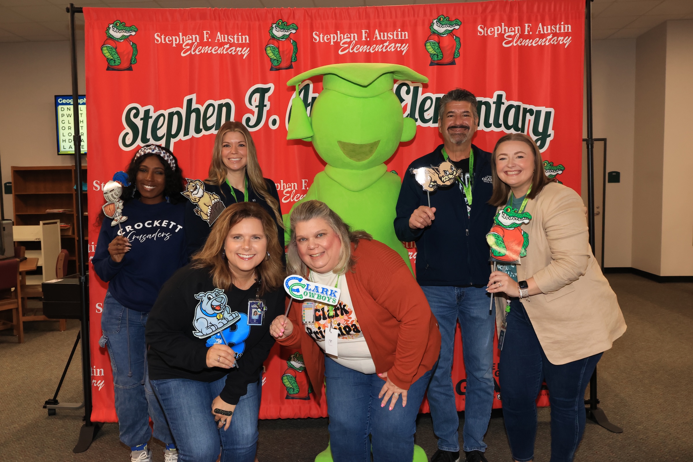 campus administrators pose in front of a stephen f austin step and repeat