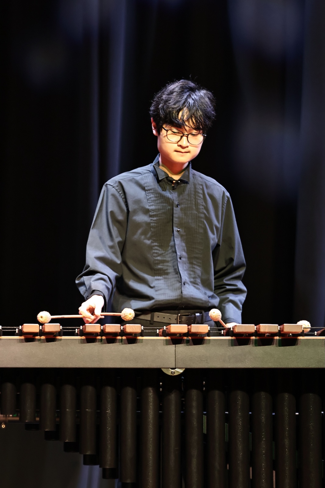 Daniel Pak playing his instrument on stage in a black suit