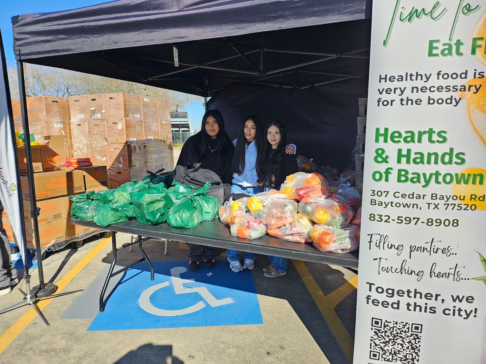 students standing with produce in food drive tent outside