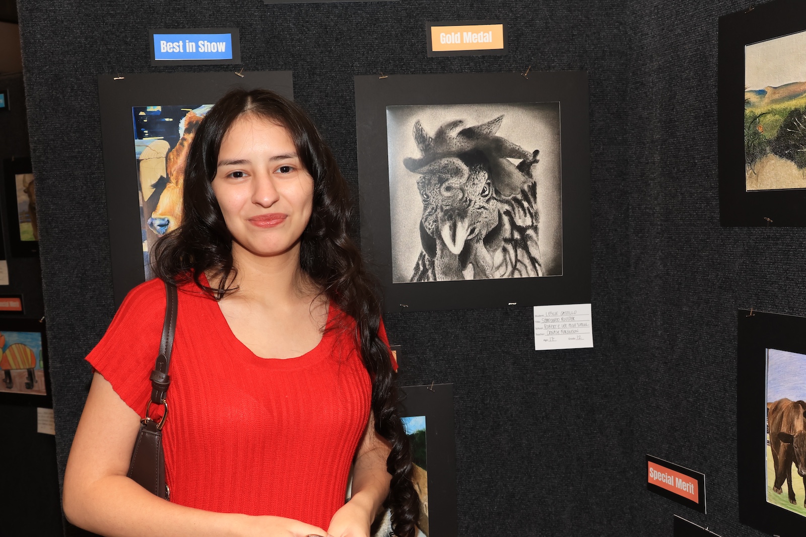 Student stands in front of her charcoal drawing for rodeo art