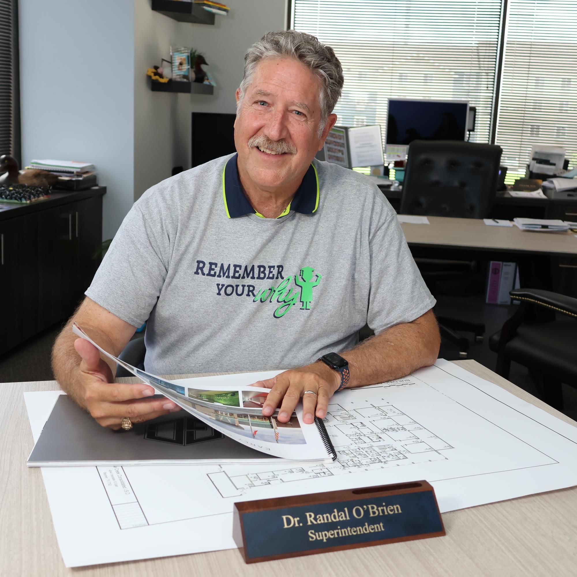 Dr. Randal OBrien at his desk looking through floorplans and concepts for new facilities